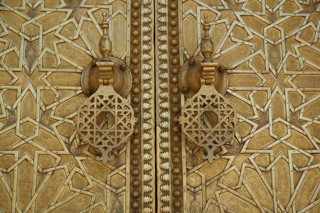 Ornate golden doors with geometric patterns and traditional metal door knockers.
