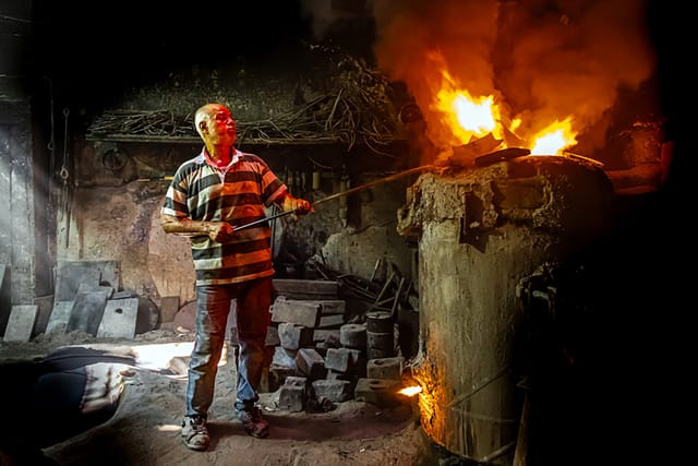 A smelter tends a blazing traditional furnace.
